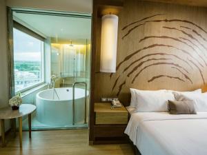 a hotel room with a bed and a bath tub at Mövenpick Siam Hotel Na Jomtien Pattaya in Na Jomtien