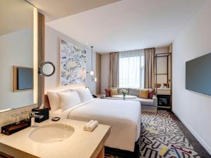 um quarto de hotel com uma cama grande e um lavatório em Mercure Kuala Lumpur Glenmarie em Shah Alam