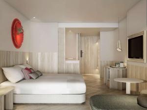 ein Schlafzimmer mit einem großen weißen Bett und einem TV in der Unterkunft Mercure Rayong Lomtalay Villas & Resort in Mae Pim