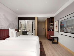 a bedroom with a large white bed and a bathroom at Swissôtel Clark Philippines in Clark