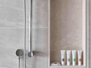 een douche met een spiegel en tandenborstels op een plank bij Swissôtel Clark Philippines in Clark