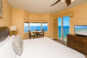 a bedroom with a bed and a television and a balcony at Tidewater2808 in Panama City Beach