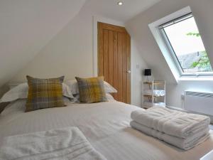 a bedroom with a white bed with pillows and a window at Bonnie Cottage - Uk40057 in Aberfeldy