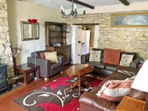 a living room with leather furniture and a stone wall at Ashley Cottage in Colsterworth