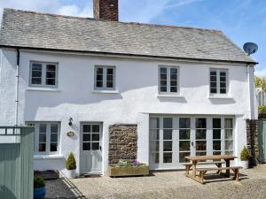 a white house with a picnic table in front of it at The Coach House in Chulmleigh