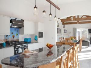 a kitchen with a large black counter top and wooden chairs at The Cartshed in Slindon