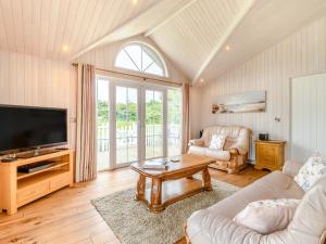 uma sala de estar com uma televisão, um sofá e uma mesa em Acacia Lodge em Willington