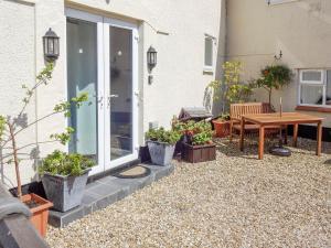 a patio with potted plants and a wooden table at The Snug in Amlwch