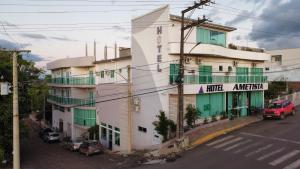 a white building with green windows and a street at Hotel Ametista in Ametista do Sul