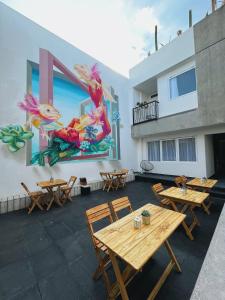 eine Terrasse mit Tischen und ein Wandbild an der Seite eines Gebäudes in der Unterkunft Casa Oxa Hotel in Querétaro