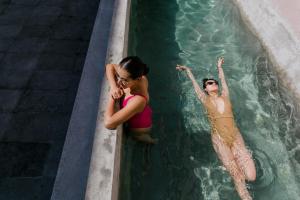 Dos mujeres están en una piscina en Casa Oxa Hotel en Querétaro