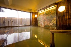 a room with a tub with a painting on the wall at Shikishimaso in Higashikawa