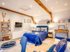 ein Schlafzimmer mit einem blauen Bett und einem Sofa in der Unterkunft Dassett View in Fenny Compton