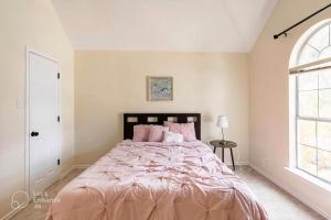um quarto com uma cama grande e lençóis cor-de-rosa em Grand Gem for Families - Games, Office, Backyard em Carrollton