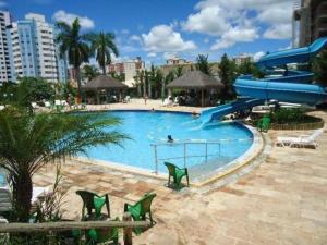 a large swimming pool with green chairs and a slide at Apart hotel em Caldas Novas in Caldas Novas