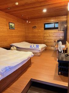 Zhong Ming Ju Taoyi Fang في Fanlu: سريرين في غرفة بجدران خشبية ومكتب