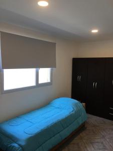 Un dormitorio con una cama azul y una ventana en Departamento nuevo a estrenar en Necochea