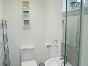 Baño blanco con lavabo y espejo en Barn Owl Cottage, en Inver