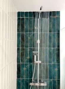 a shower in a bathroom with green tiles at Reves Bleus in Le Gosier