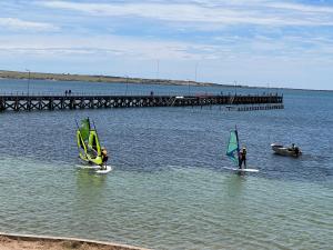 dwie osoby są windsurfing w wodzie w pobliżu molo w obiekcie Beachside & Jetty View Apartment 5 - Harbour Master Apt w mieście Streaky Bay