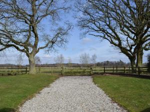 einen Kiesweg auf einem Feld mit Bäumen und einem Zaun in der Unterkunft The Annex in Chelford