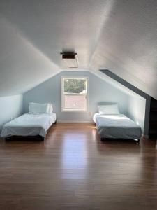a attic room with two beds and a window at Cozy Home for Family & Friends Gathering in Beaverton