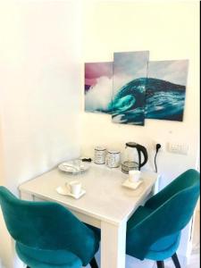 a table with two green chairs and two paintings at Seven Luxury Suites in Belgrade