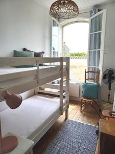 een slaapkamer met een stapelbed en een raam bij DOLUS, Maison à 10 min. de la plage! in Dolus d'Oléron