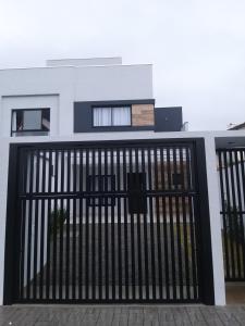 een huis met een zwarte poort ervoor bij Bellacasa Rua Leão in Bombinhas