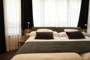 una camera da letto con un grande letto con cuscini bianchi e neri di Hotel Lux Santiago a Santiago de Compostela