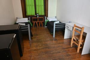 a room with two beds and a desk and green curtains at 06 Central Hostel Buenos Aires in Buenos Aires