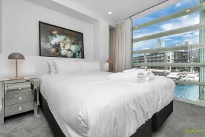 Un dormitorio con una gran cama blanca y una ventana en QV Modern Waterfront 2-bedroom apartment - 079 en Auckland