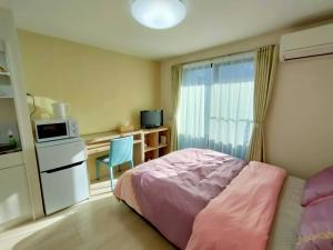 KIKI HOUSE 新小岩 في طوكيو: غرفة نوم مع سرير ومكتب مع ميكروويف