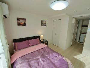東京的住宿－KIKI HOUSE 新小岩，一间卧室配有一张带紫色毯子的床