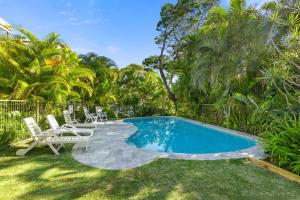 Una piscina en un patio con dos sillas y una mesa. en Sundowner 3 - Ocean Views near Noosa Main Beach, en Noosa Heads