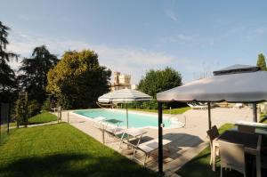 a swimming pool with chairs and umbrellas in a yard at Villa Torricelli Scarperia - Il Giardinetto Residence in Scarperia
