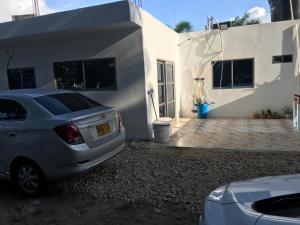 a car parked in front of a white house at Cabaña la isla in Coveñas