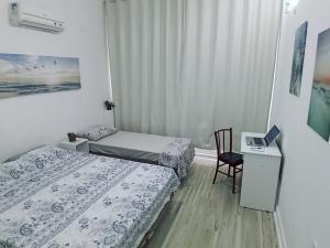um quarto com 2 camas, uma secretária e uma cadeira em Ponta da Praia amplo 3dorm 3ban frente ao mar em Santos