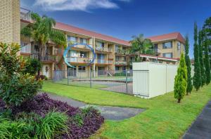 an apartment building with a fence in front of a yard at Aqua on Bribie 100 metres to Beach and Shops in Bongaree