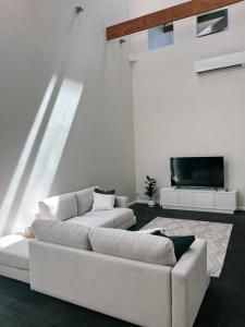 a living room with two white couches and a tv at Bendigo Townhouse - Walk to the CBD in Bendigo