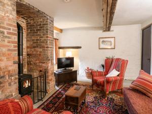 a living room with a brick fireplace and red chairs at Gatehouse Croft in Newton Regis