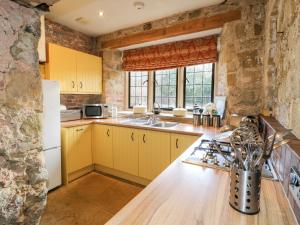 eine Küche mit gelben Schränken und einem weißen Kühlschrank in der Unterkunft Gatehouse Croft in Newton Regis