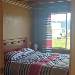 1 dormitorio con 1 cama grande y ventana en Refugio Hualaihue, en Hornopirén