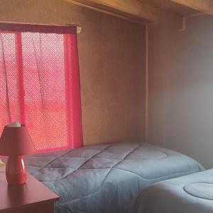 a bedroom with a bed and a red window at Refugio Hualaihue in Hornopiren
