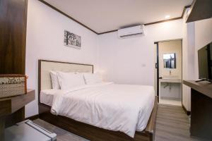 a bedroom with a white bed and a television at De Thaphae Chiangmai in Chiang Mai