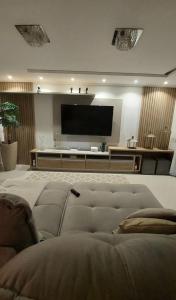 a living room with a couch and a flat screen tv at Casa de luxo em condomínio in Arraial do Cabo