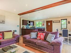 a living room with two purple couches and a kitchen at Foxglove Lodge in Holsworthy