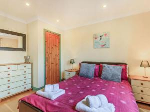 um quarto com uma cama rosa e toalhas em Foxglove Lodge em Holsworthy