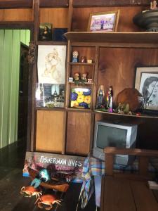 a living room with a tv and a shelf with toys at Fisherman Guesthouse in Ko Yao Noi