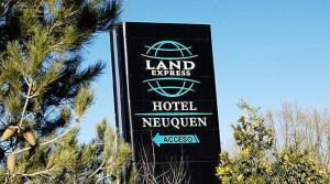 a sign for the land express hotel in front of a tree at Land Express Neuquén in Neuquén